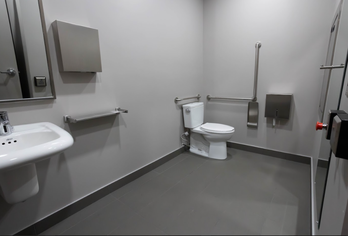 View inside accessible washroom on the main floor. There is an L shaped handlebar by the toilet.