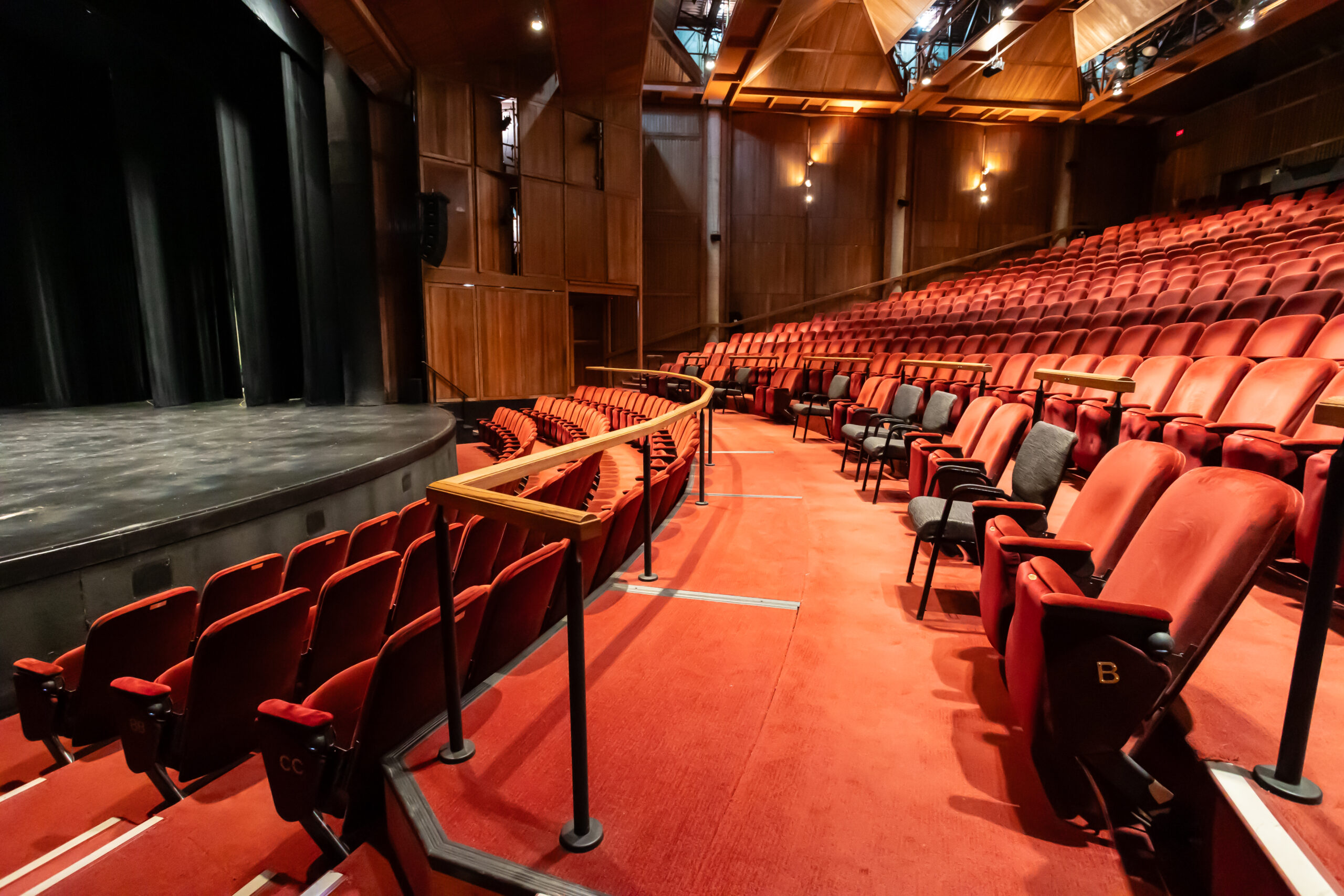 A photograph of a wide and spacious row in the Shoctor Theatre, with red fixed seats and grey moveable seats.